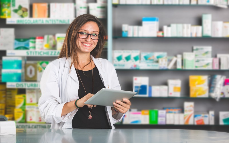 Beautiful Pharmacist with Digital Tablet in a Drugstore